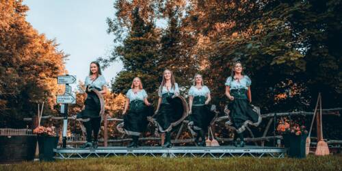 five women performing Irish dancing on an outdoor stage for a tourism experience.